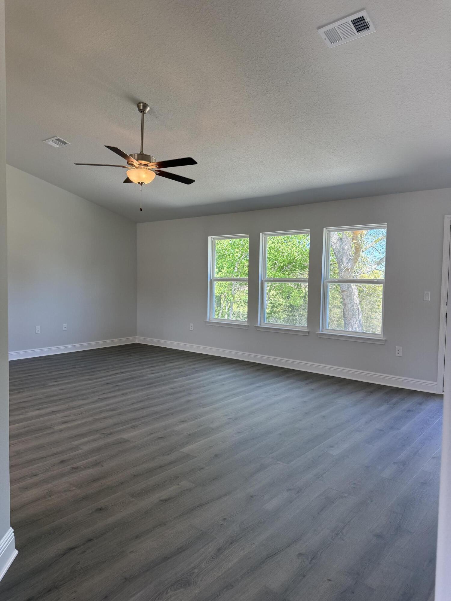 6014 Crocket Cove Crestview, FL 32539 - Photo 21 of 29 an empty room with wooden floor chandelier fan and windows