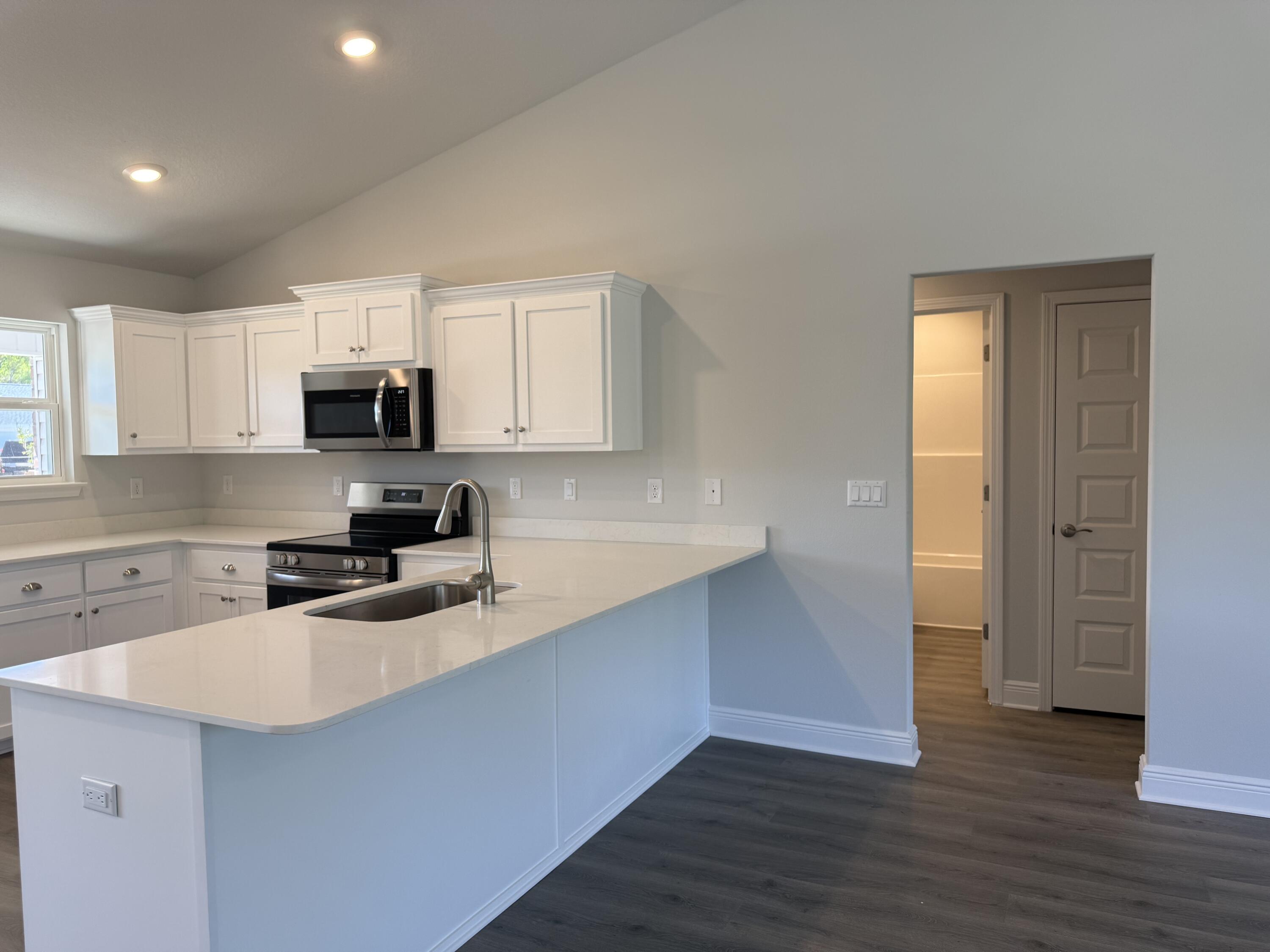 6014 Crocket Cove Crestview, FL 32539 - Photo 9 of 29 a kitchen with wooden cabinets a sink a stove a microwave and wooden floor