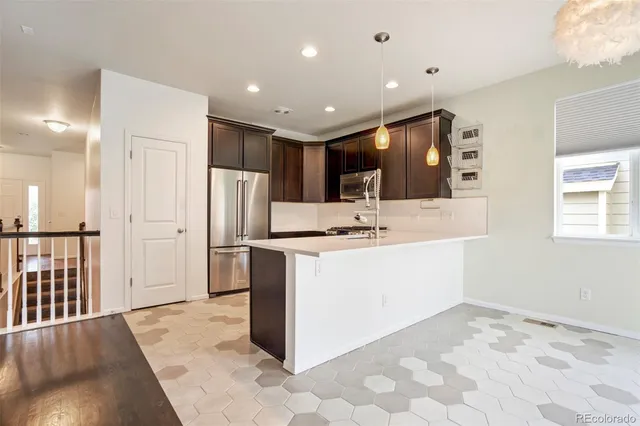 a kitchen with stainless steel appliances kitchen island granite countertop a refrigerator and a sink