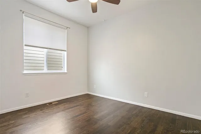 an empty room with wooden floor cabinet and windows