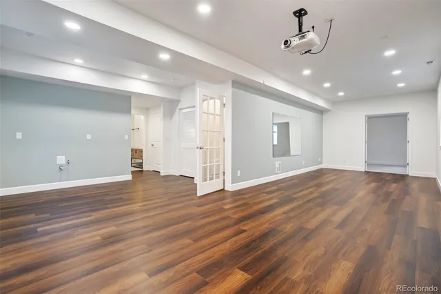 a view of an empty room with wooden floor and a ceiling fan