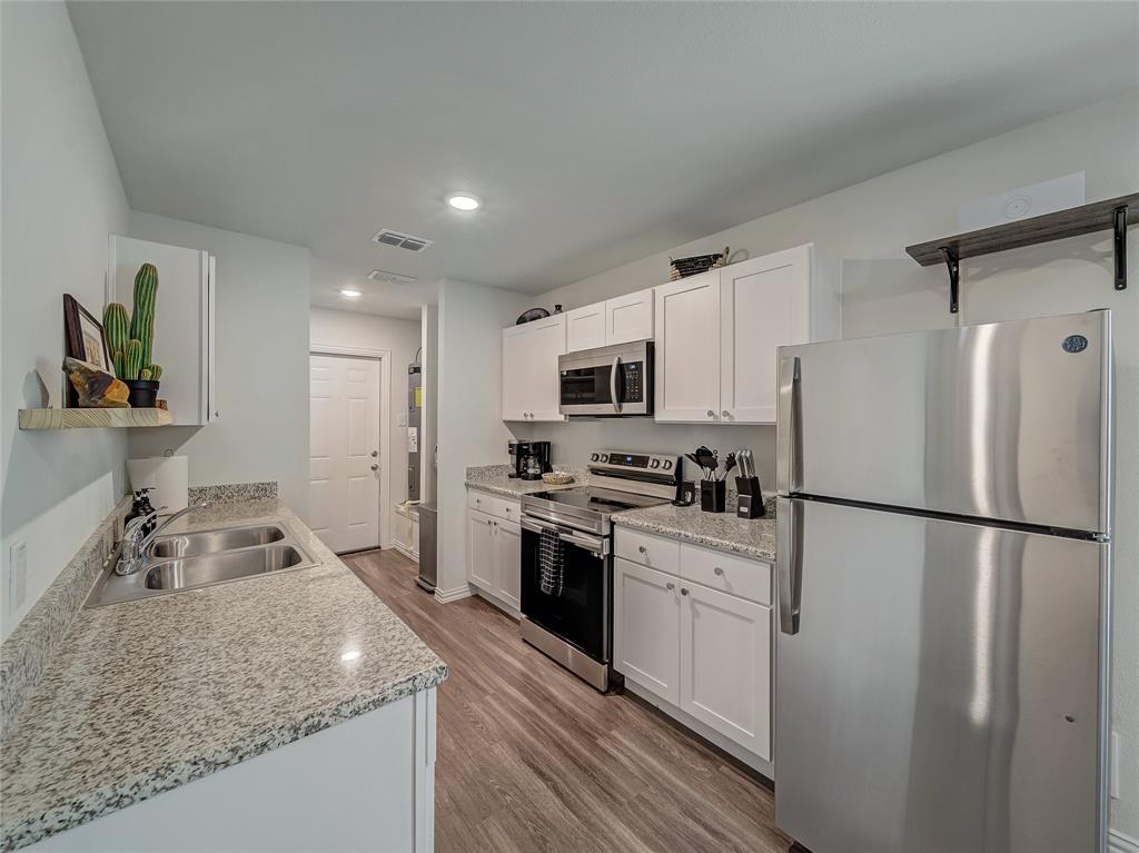 921 West 9th Street Bonham, TX 75418 - Photo 5 of 22 Kitchen with stainless steel appliances, light wood-style flooring, white cabinetry, open shelves, and recessed lighting