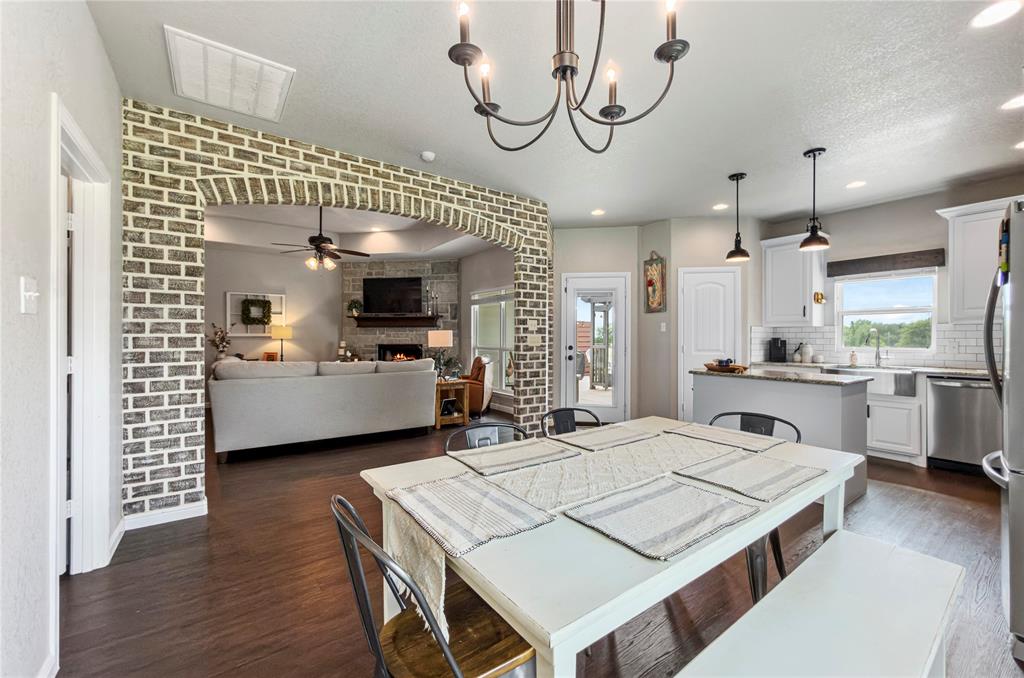 6093 Farm To Market Road 730 North Decatur, TX 76234 - Photo 7 of 28 a large white kitchen with a white stove a sink dishwasher and a dining table with wooden floor