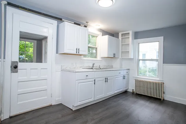 a kitchen with granite countertop white cabinets window and sink