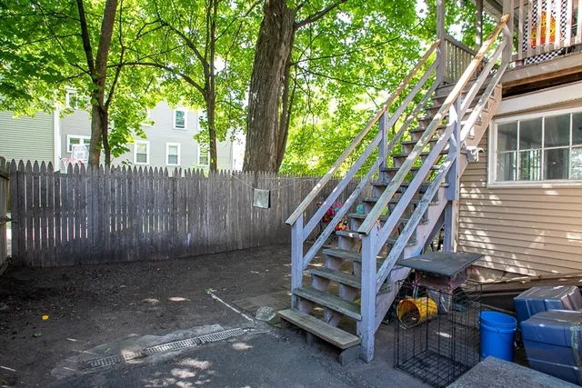 a view of backyard with wooden fence and trees