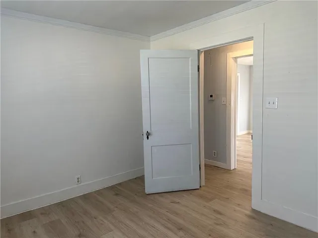 a view of an empty room with wooden floor and closet