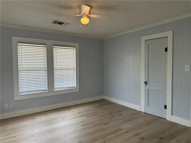an empty room with wooden floor and windows