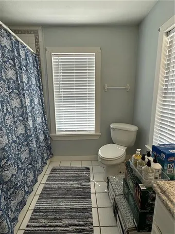 a bathroom with a granite countertop toilet a sink and a window