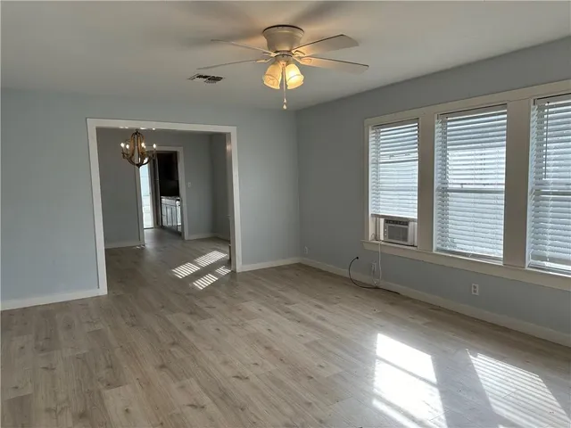 a view of empty room with wooden floor and fan