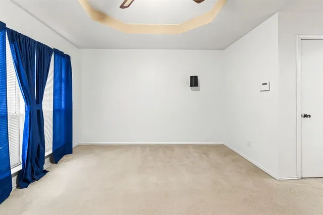 an empty room with a chandelier fan and windows