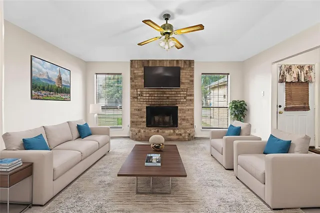 an empty room with windows fireplace and a ceiling fan