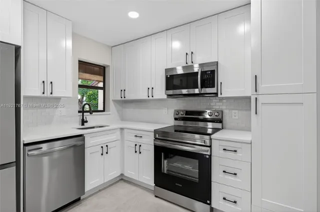 a kitchen with white cabinets stainless steel appliances and sink
