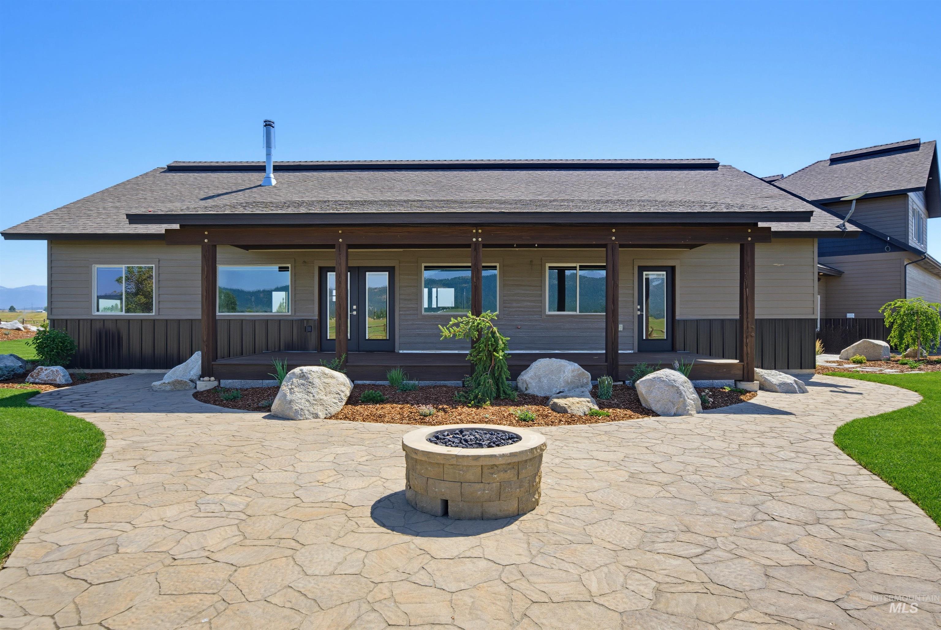 13945 Galloping Road McCall, ID 83638 - Photo 6 of 50 Expansive stone patio featuring a built-in fire pit, surrounded by a manicured lawn and decorative boulders