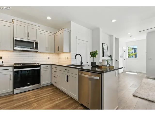 a kitchen with stainless steel appliances granite countertop a sink a stove top oven a counter space and cabinets