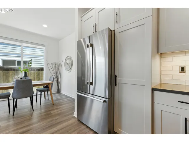 a kitchen with stainless steel appliances a refrigerator a microwave a dining table and chairs