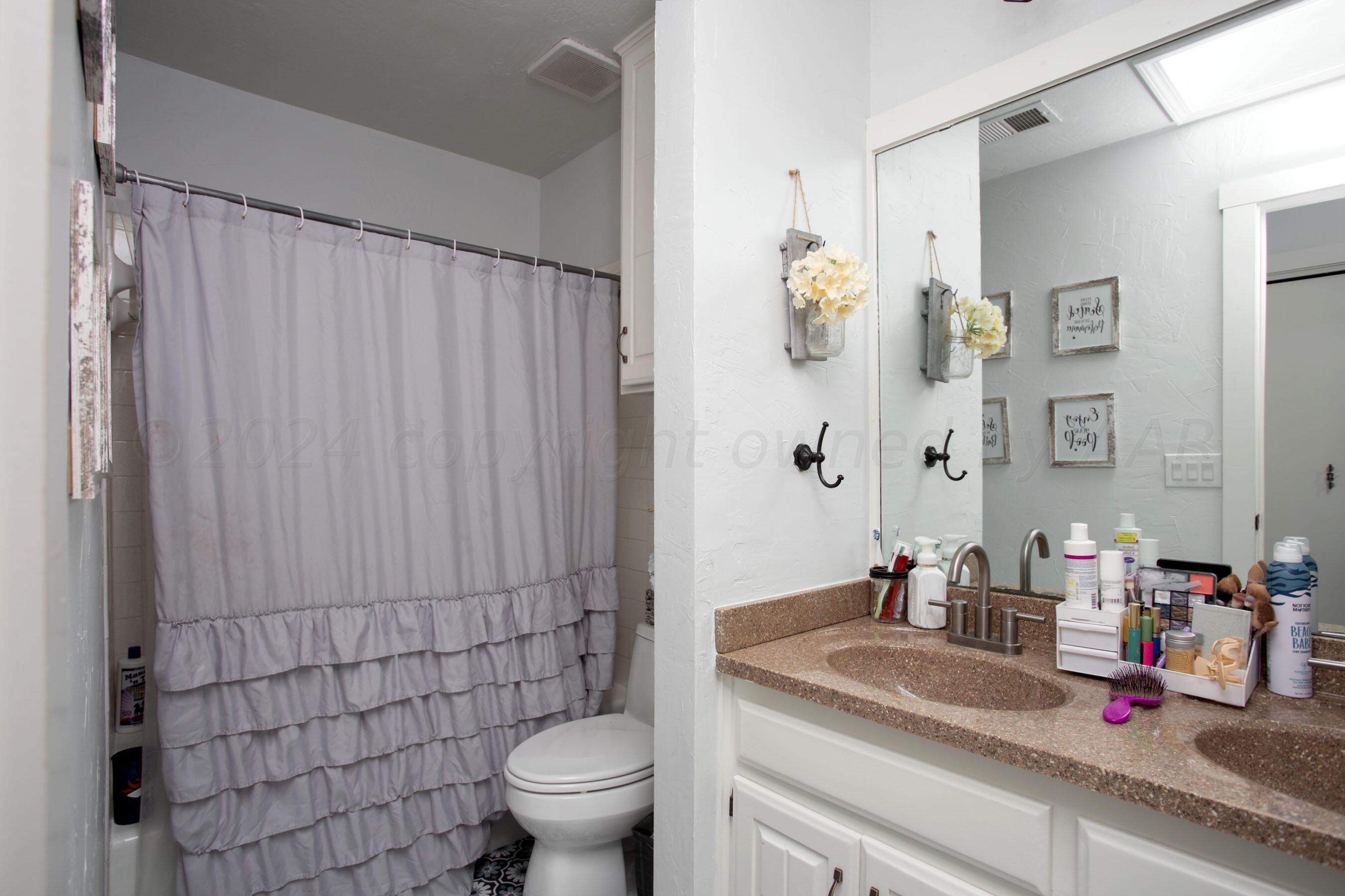 5109 Navajo Trail Amarillo, TX 79110 - Photo 17 of 29 a bathroom with a granite countertop sink a toilet and a mirror