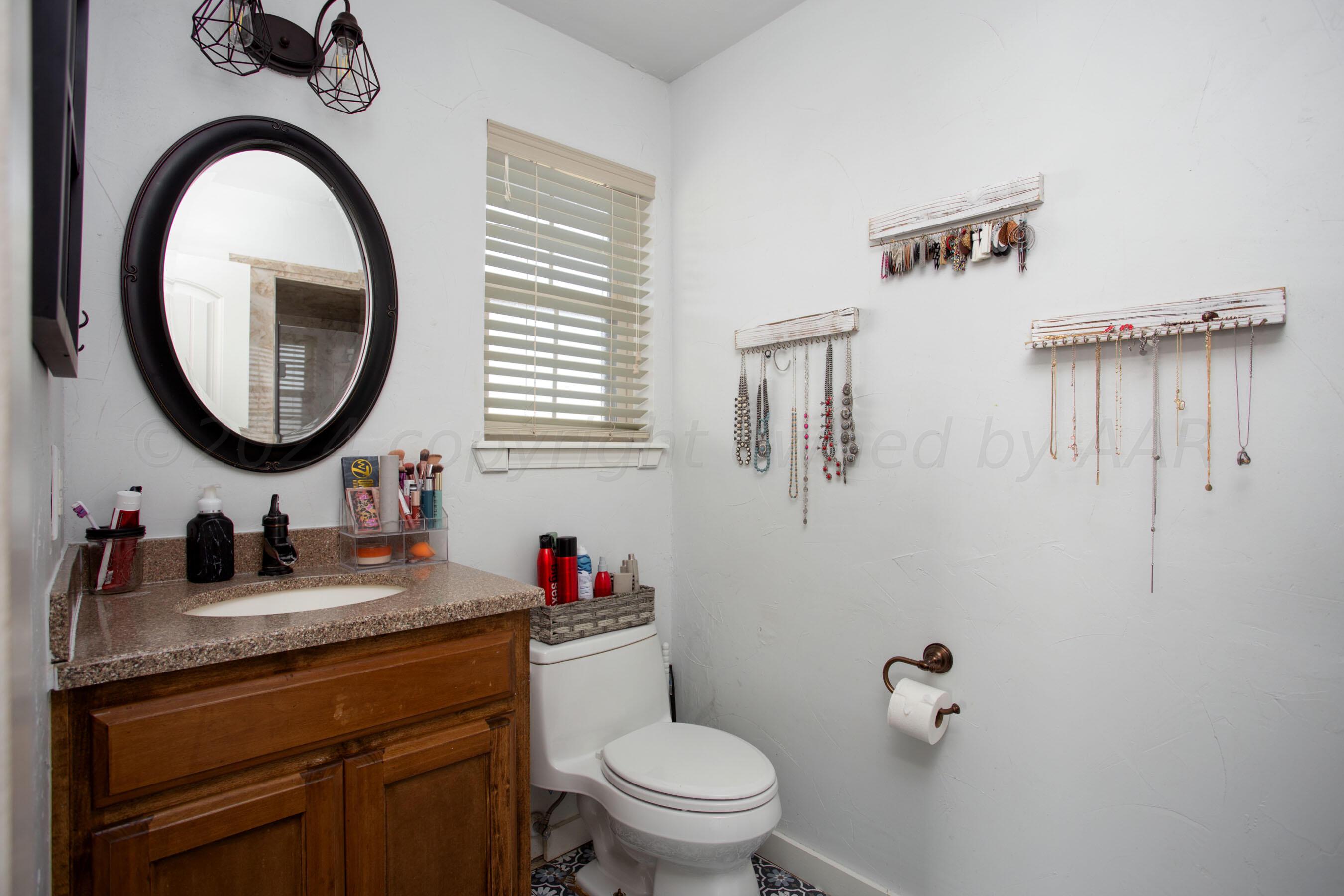 5109 Navajo Trail Amarillo, TX 79110 - Photo 23 of 29 a bathroom with a granite countertop toilet a sink and a mirror