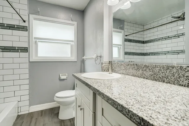 a bathroom with a granite countertop sink toilet and shower