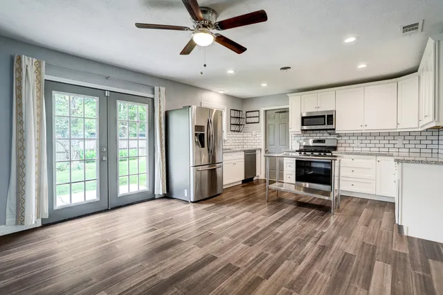 a kitchen with stainless steel appliances a stove top oven a sink dishwasher a refrigerator and cabinets with wooden floor