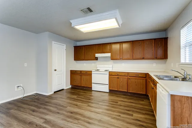 a kitchen with stainless steel appliances granite countertop wooden cabinets a stove top oven a sink and dishwasher with wooden floor