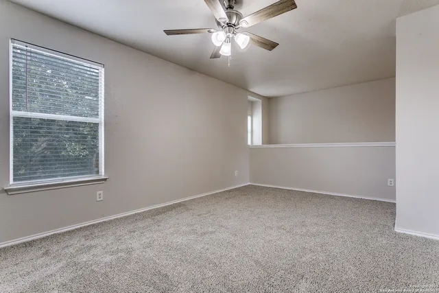 an empty room with a window and a fan
