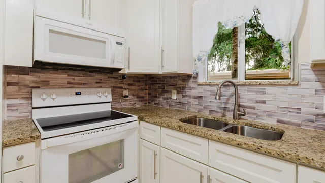 a kitchen with granite countertop white cabinets and white appliances