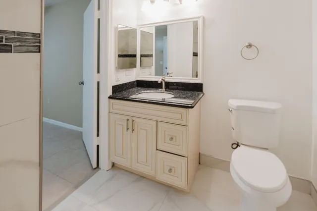 a bathroom with a granite countertop sink a toilet and shower