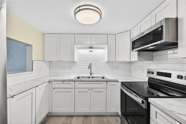 a kitchen with white cabinets stainless steel appliances and sink