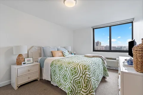 a bedroom with a bed and a dresser next to a window