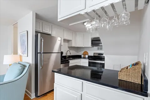 a kitchen with stainless steel appliances granite countertop a refrigerator a stove a sink dishwasher and a refrigerator with wooden floor