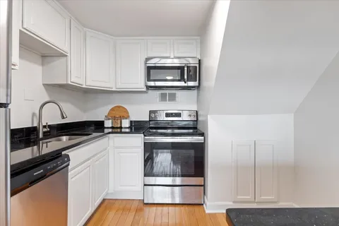 a kitchen with stainless steel appliances granite countertop a stove a sink and a microwave