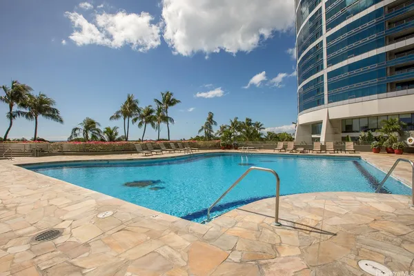 a view of a swimming pool with a lawn chairs under an umbrella