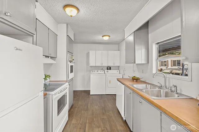 a kitchen with sink a refrigerator and white cabinets