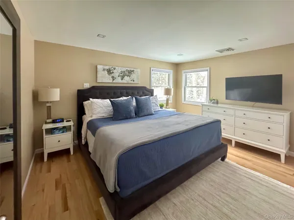 a bedroom with a bed and a flat tv screen on dresser