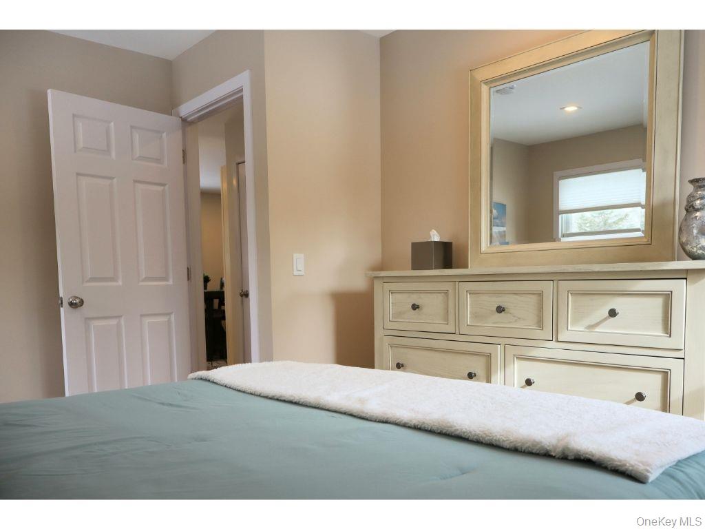 38 Woodridge Road Hampton Bays, NY 11946 - Photo 18 of 24 a bedroom with a bed and a mirror