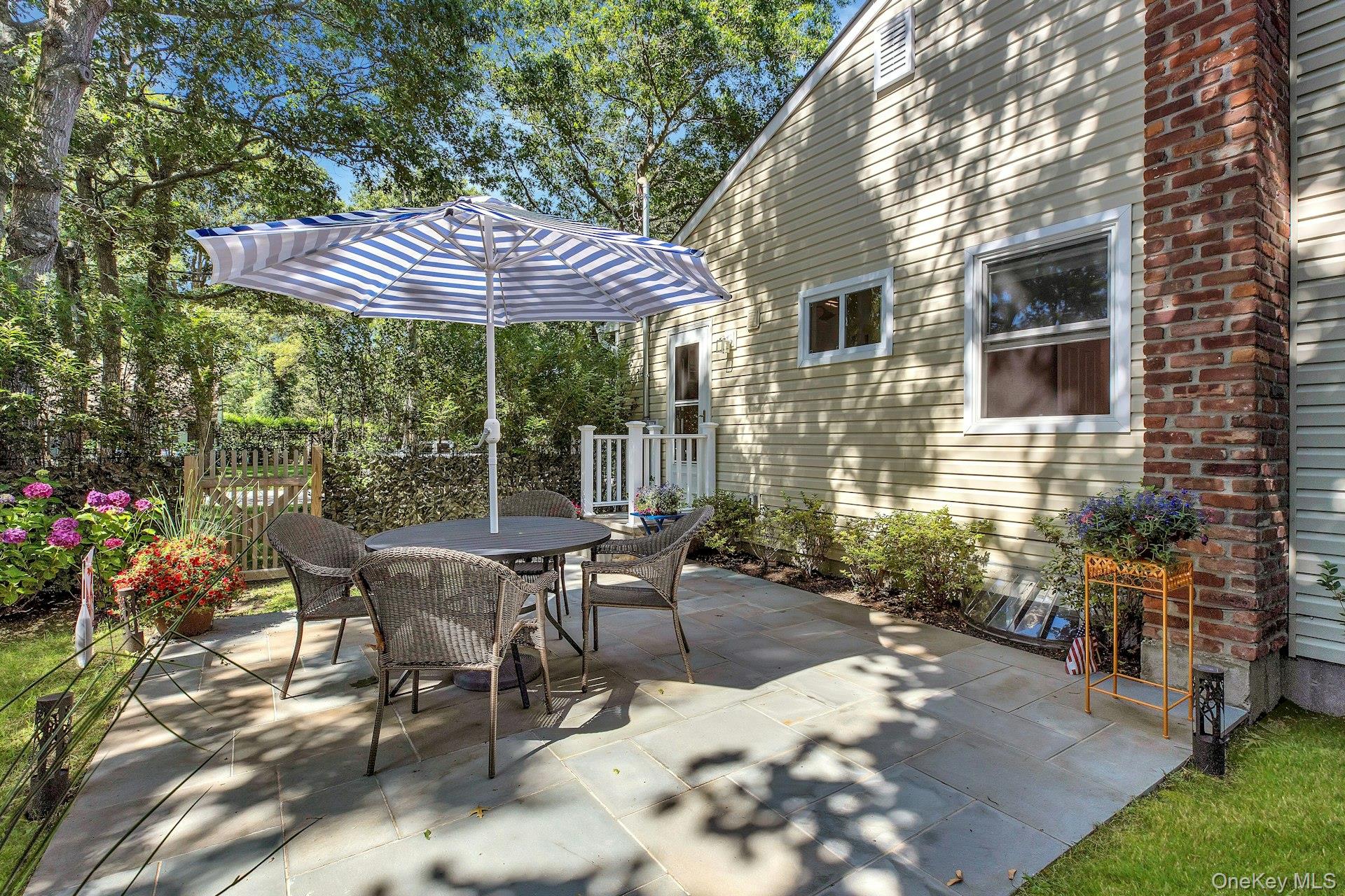 38 Woodridge Road Hampton Bays, NY 11946 - Photo 20 of 24 a patio with a table and chairs under an umbrella