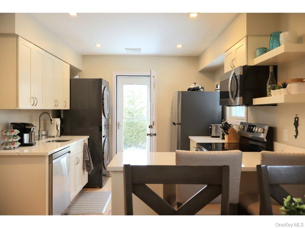 38 Woodridge Road Hampton Bays, NY 11946 - Photo 8 of 24 a kitchen with stainless steel appliances a stove refrigerator sink microwave and cabinets