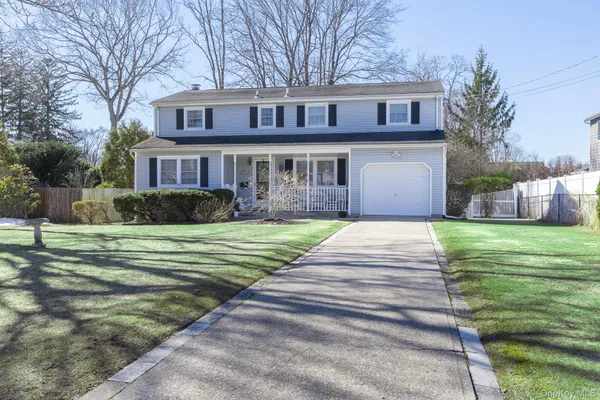 a front view of a house with a garden and trees
