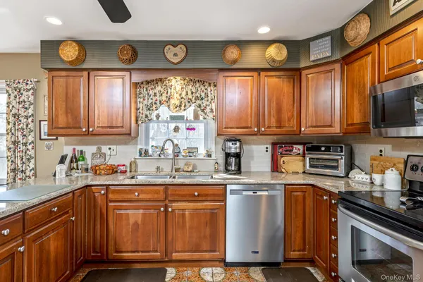a kitchen with stainless steel appliances granite countertop a sink a stove a refrigerator cabinets and a window