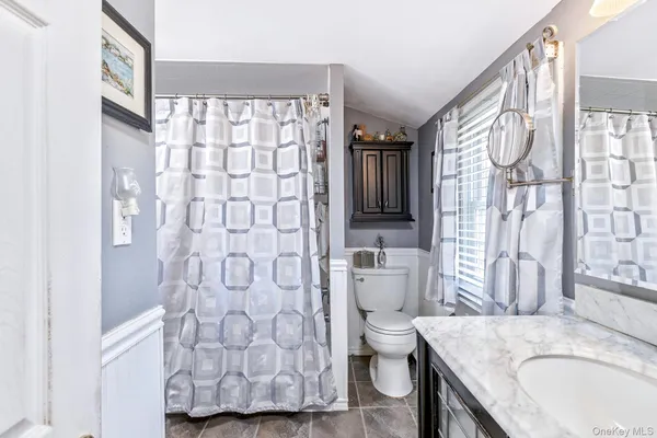 a bathroom with a granite countertop bathtub sink vanity mirror and toilet
