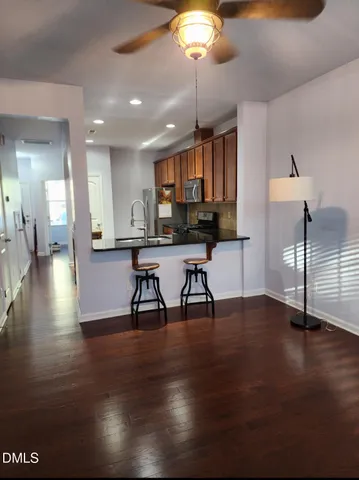 a view of a kitchen with stainless steel appliances granite countertop a stove top oven a dining table and chairs with wooden floor