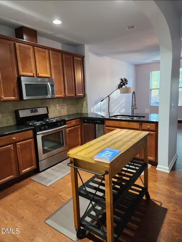 a kitchen with stainless steel appliances kitchen island granite countertop a stove top oven a sink a dining table and chairs