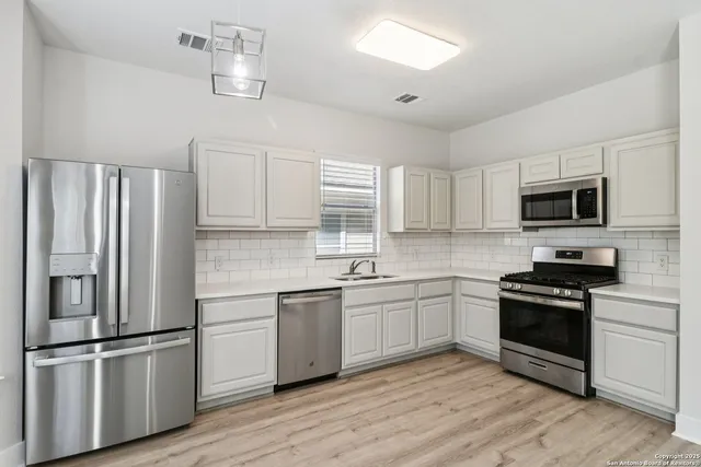 a kitchen with cabinets stainless steel appliances and wooden floor