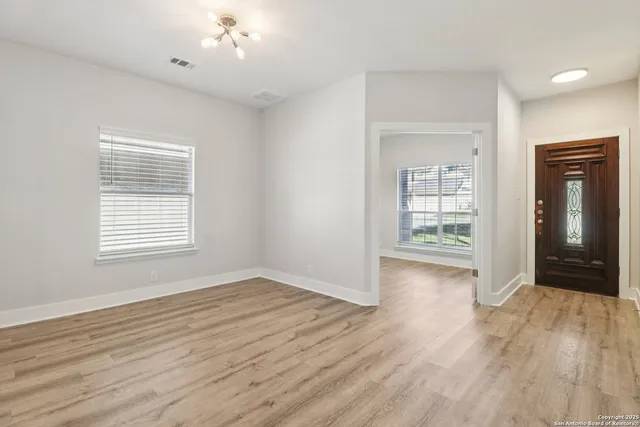 an empty room with wooden floor cabinet and windows