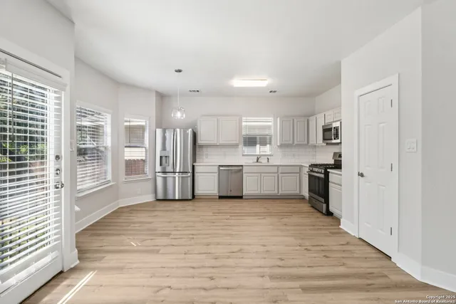 a large white kitchen with stainless steel appliances granite countertop a large counter top a sink and a refrigerator