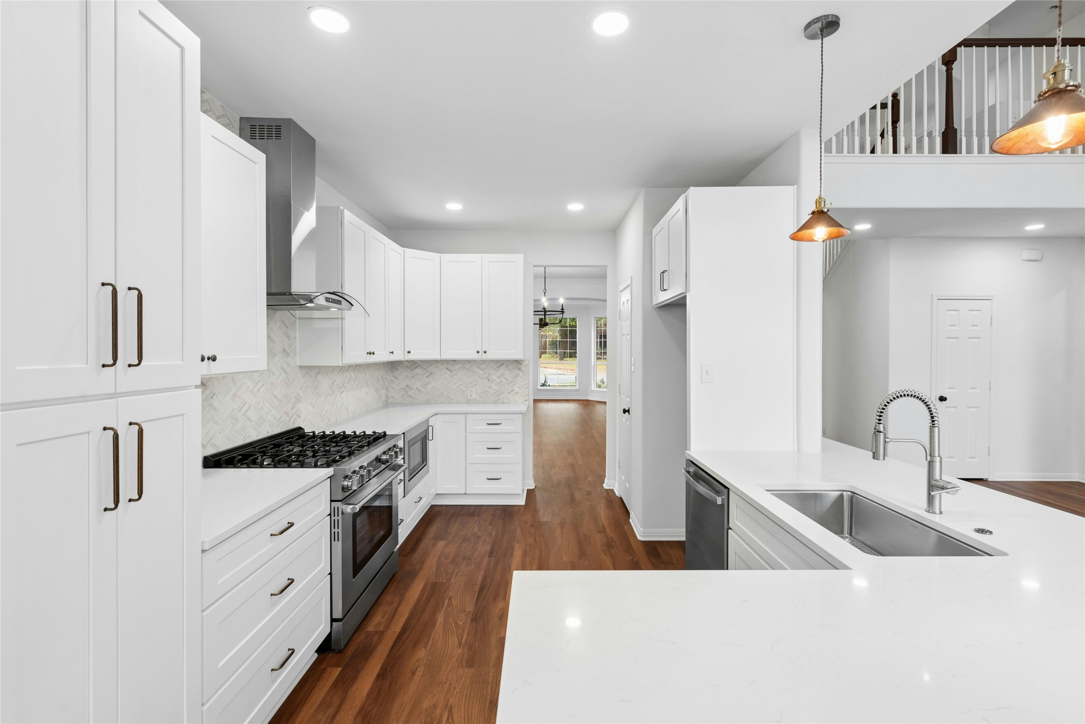 813 Caribou Ridge Trail Pflugerville, TX 78660 - Photo 2 of 39 Stunning chef’s kitchen featuring quartz countertops, custom cabinetry, a professional gas range with vent hood, designer backsplash, and warm luxury flooring in an open-concept layout.