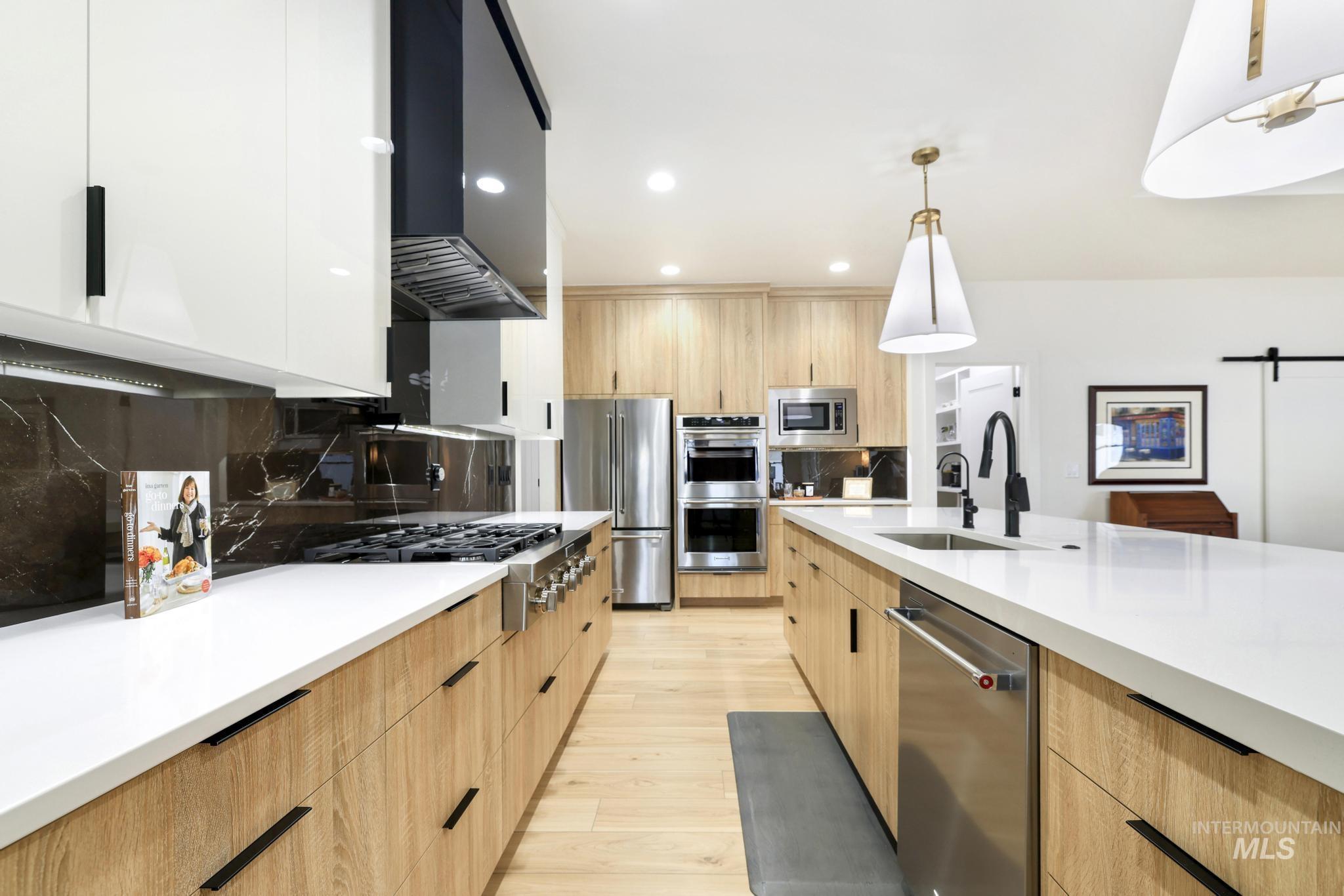 3140 Moonrise Road Twin Falls, ID 83301 - Photo 12 of 39 Kitchen featuring modern cabinets, a barn door, light wood finish cabinets, extractor fan, and stainless steel appliances