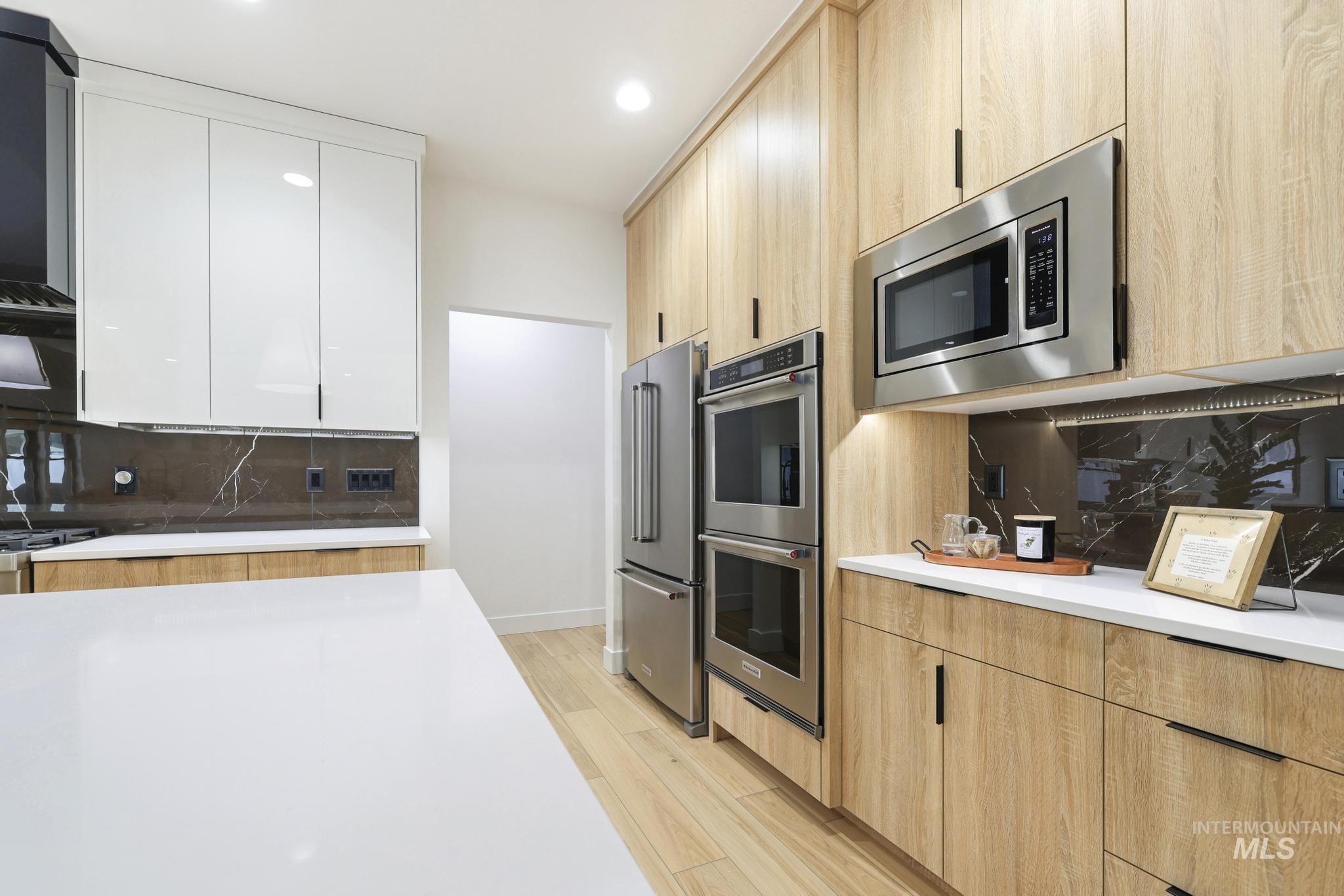 3140 Moonrise Road Twin Falls, ID 83301 - Photo 13 of 39 Two tone kitchen featuring decorative backsplash, modern cabinets, stainless steel appliances, light wood finished floors, and recessed lighting