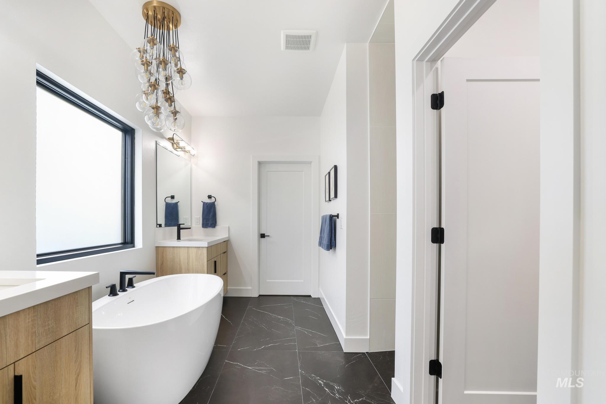 3140 Moonrise Road Twin Falls, ID 83301 - Photo 23 of 39 Full bathroom featuring two vanities, a freestanding bath, and dark marble finish flooring