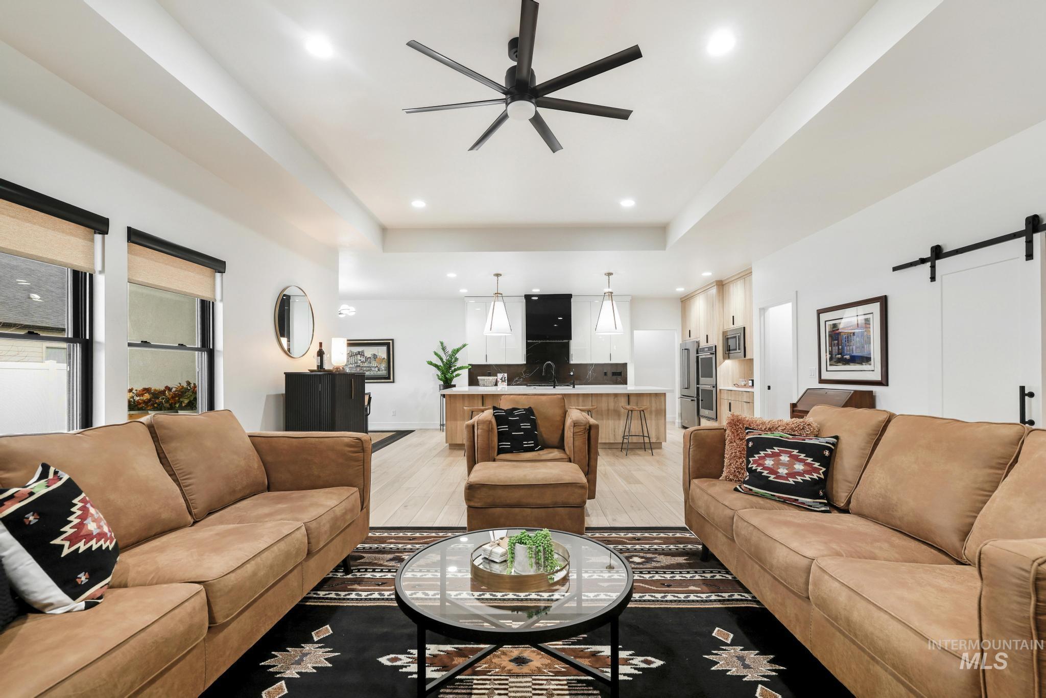 3140 Moonrise Road Twin Falls, ID 83301 - Photo 8 of 39 Living area featuring a barn door, a ceiling fan, light wood-style flooring, a tray ceiling, and recessed lighting